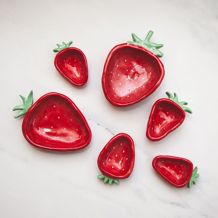 five red strawberries sitting on top of a white counter