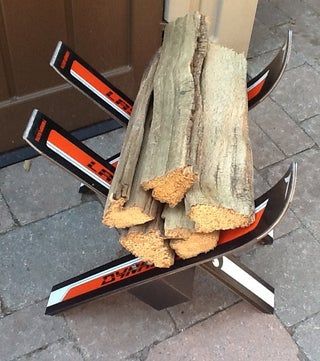 a pile of logs sitting on top of a metal stand next to a wooden door