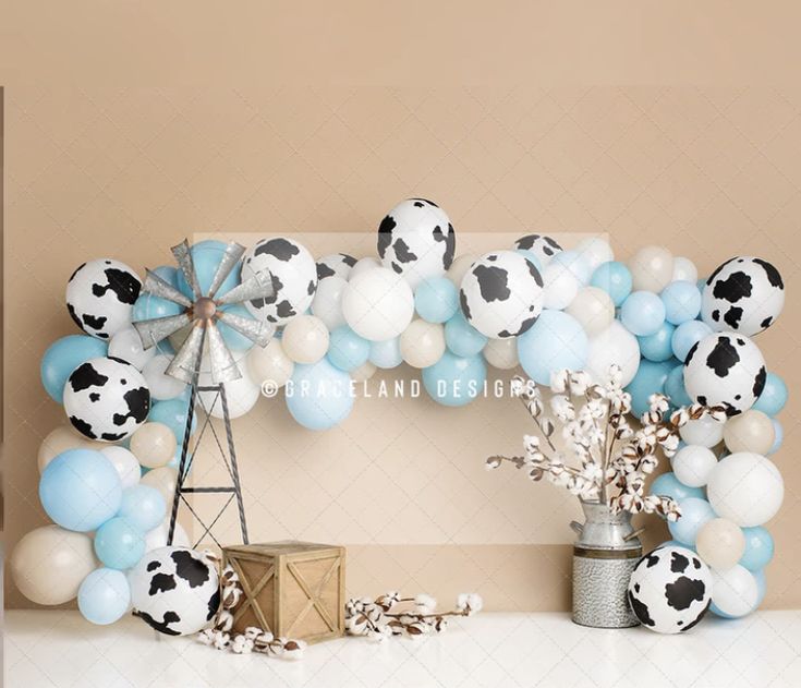 a cow themed balloon arch with balloons and decorations