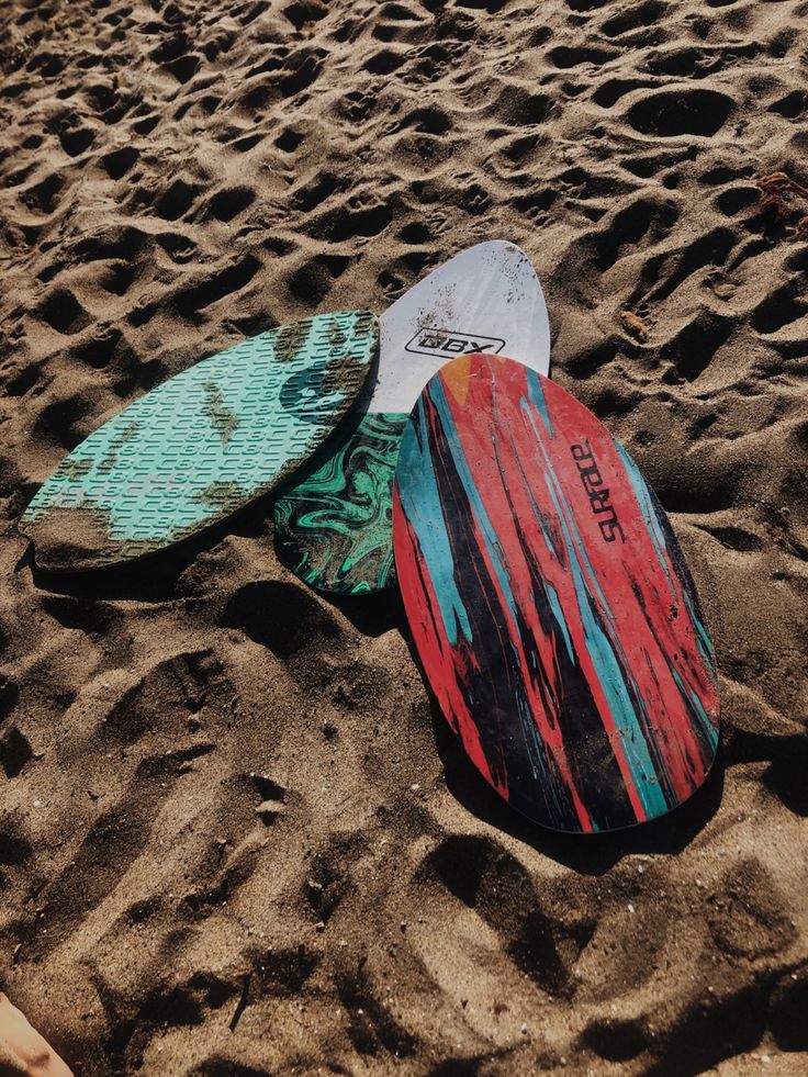 three surfboards are laying on the beach sand