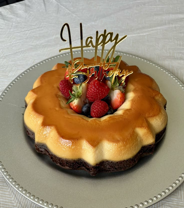 a happy birthday cake with strawberries and chocolate icing on a silver platter