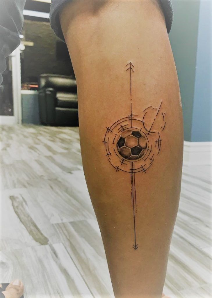 a person with a tattoo on their leg that has a compass and soccer ball in it