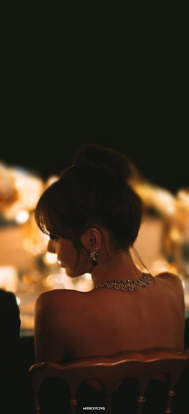 a woman sitting in a chair with her back turned to the camera and looking off into the distance