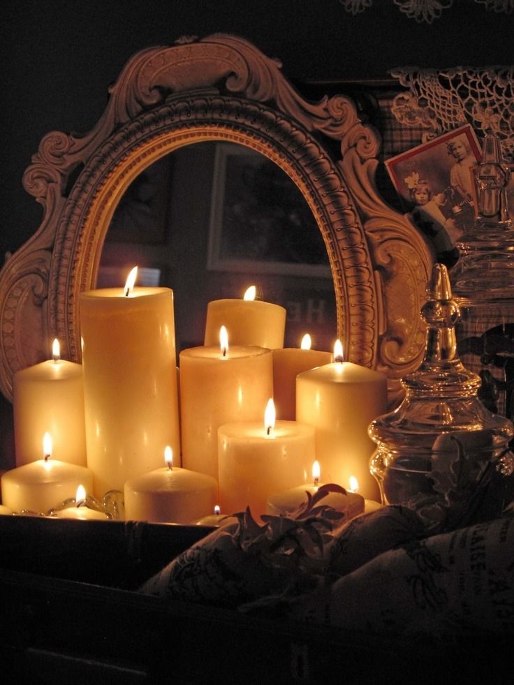 many lit candles in front of a mirror with an ornate frame around it and a candle holder on the side