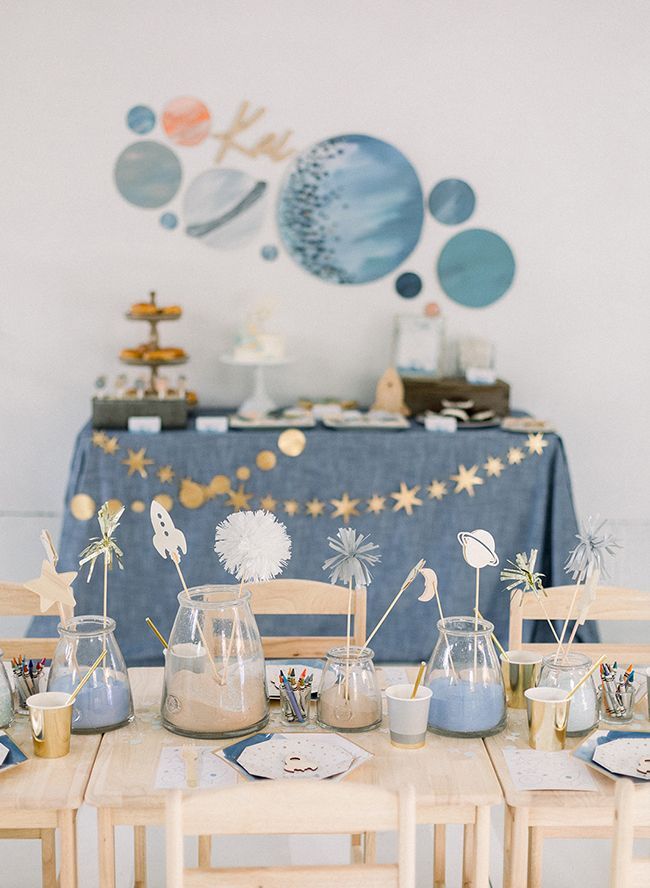 the table is set up for an outer space birthday party with blue and gold decorations