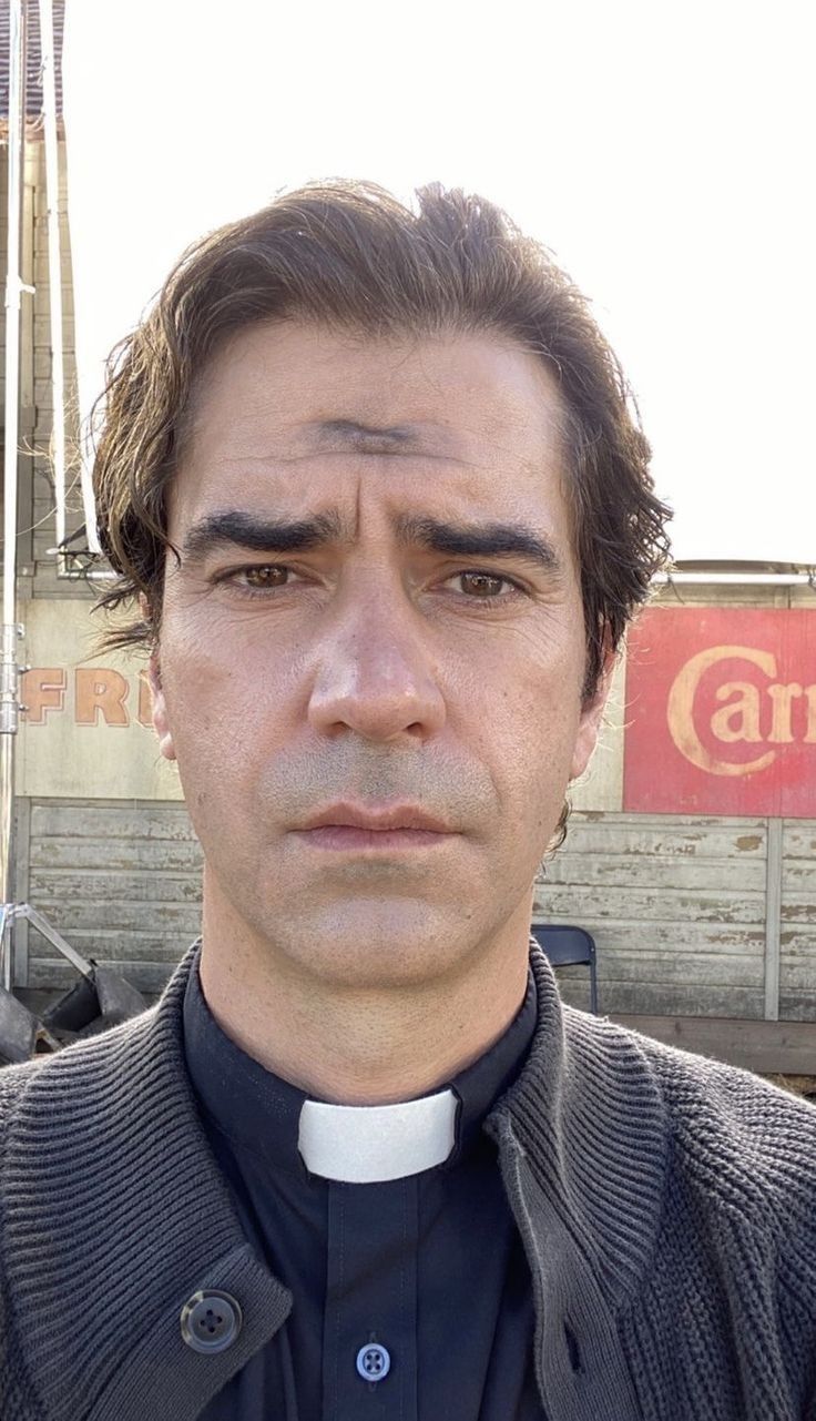 a man wearing a priest's outfit and standing in front of a building