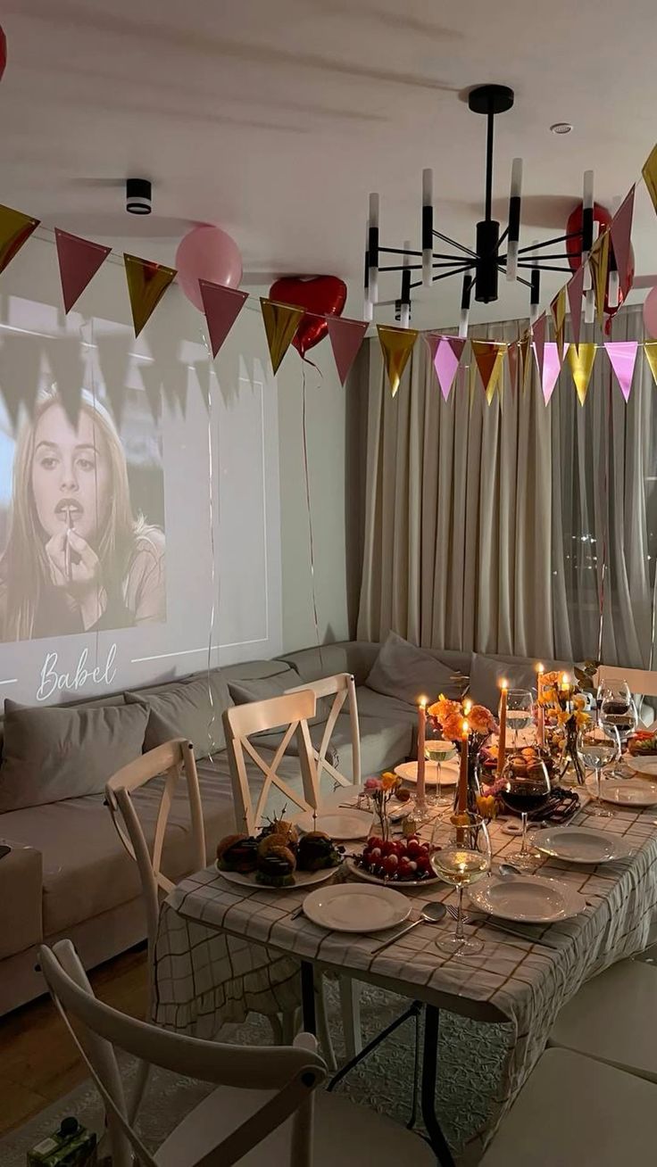 a dining room table is set up for a party with candles and balloons hanging from the ceiling