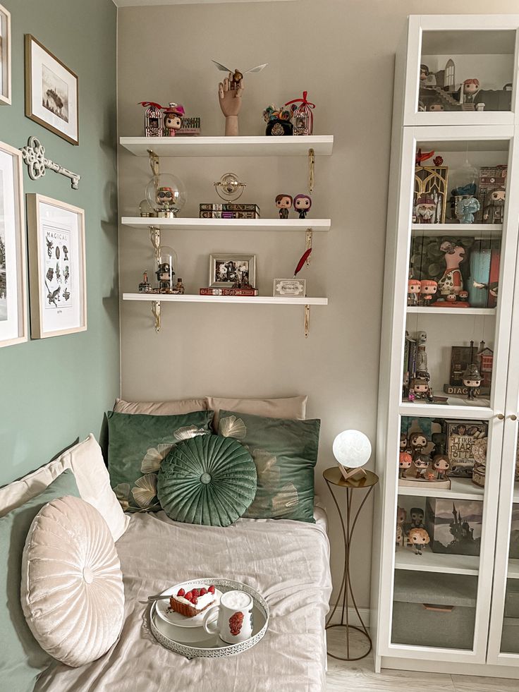 a bedroom with green walls, shelves and pictures on the wall above the headboard