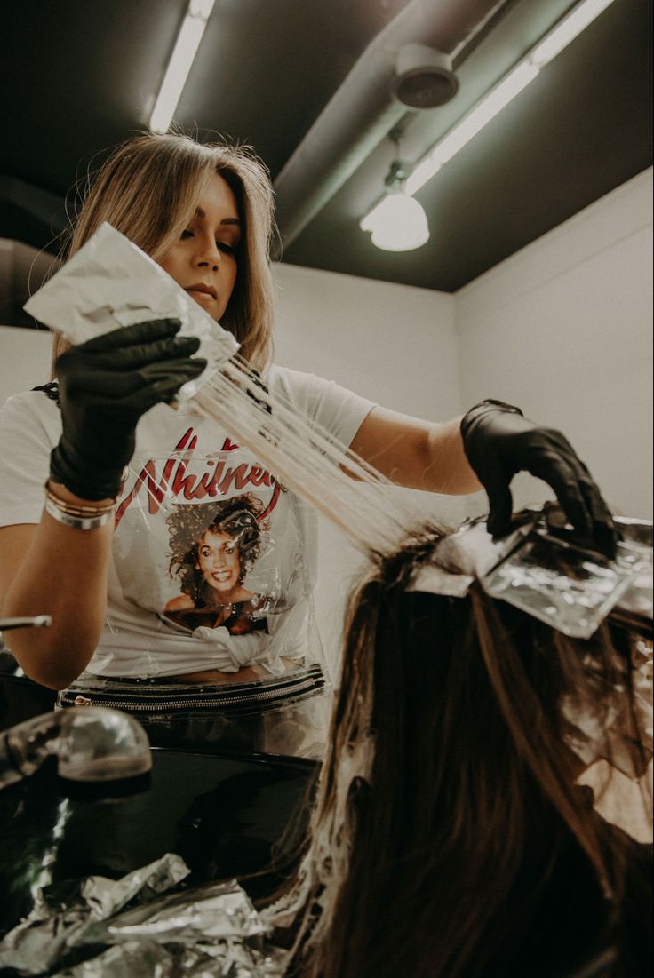 a woman is getting her hair cut at the barbershop with black gloves on