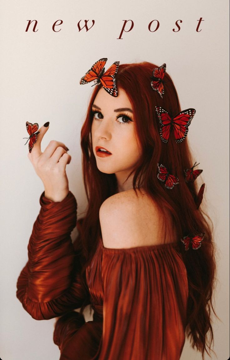 a woman with long red hair and butterflies on her head is posing for the camera