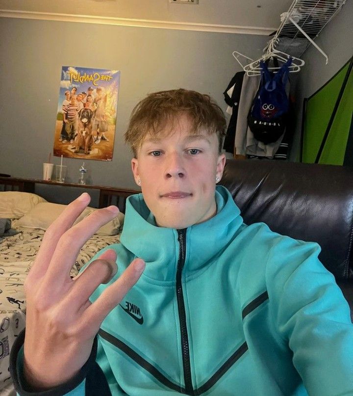 a boy sitting on a couch making the vulcan sign with his hand in front of him