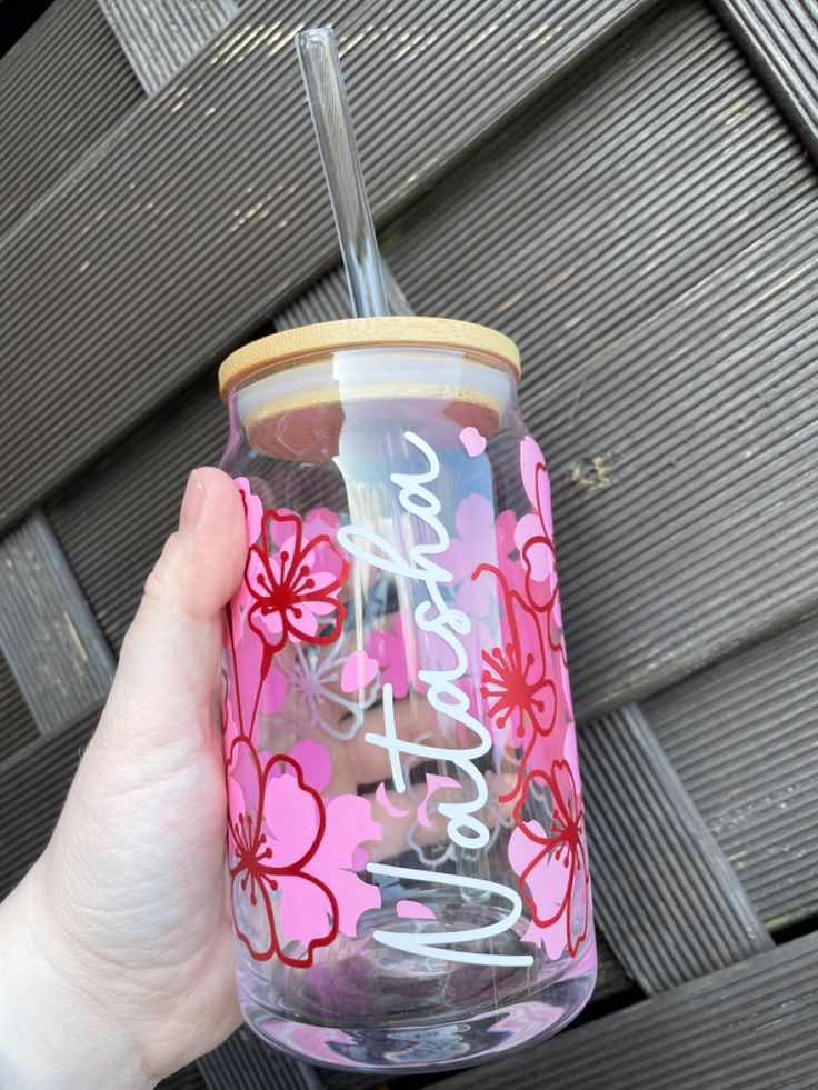 a person holding up a pink and red flowered tumbler with the words grateful on it