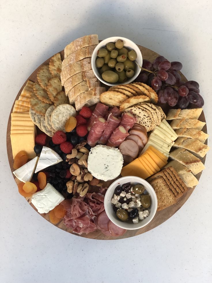 a platter filled with different types of cheeses and crackers, nuts and olives