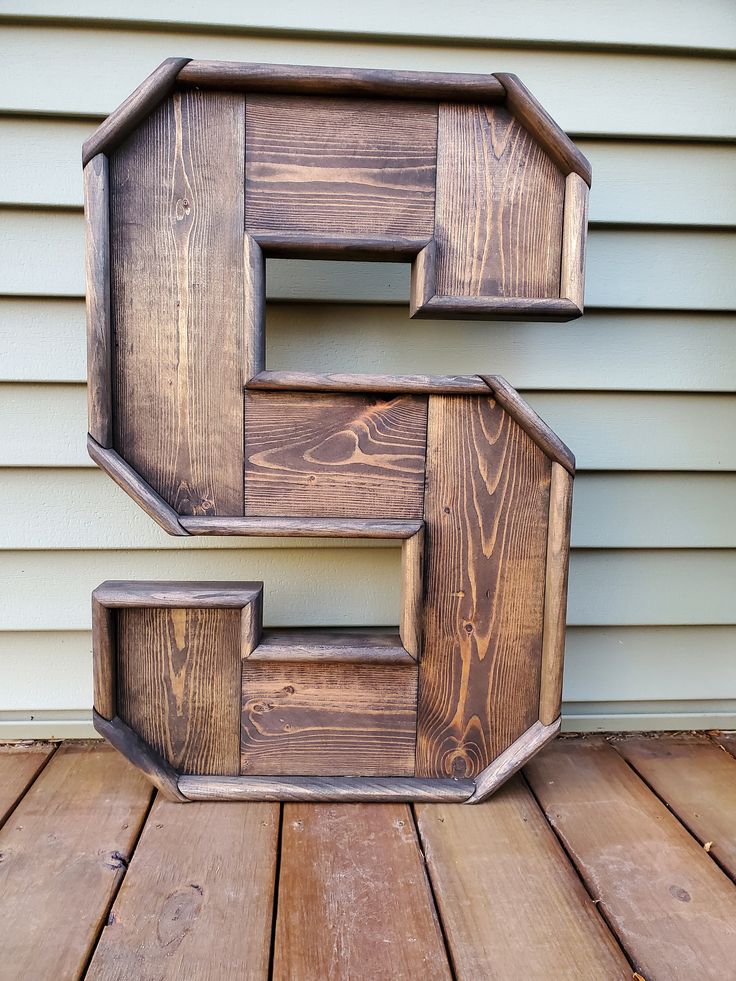 the letter e is made out of wood and has been placed on a wooden deck