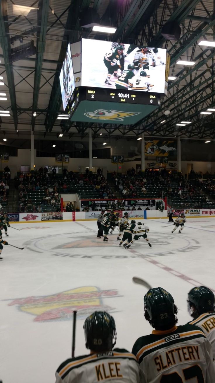 an ice hockey game is being played in a large indoor arena with people watching from the stands