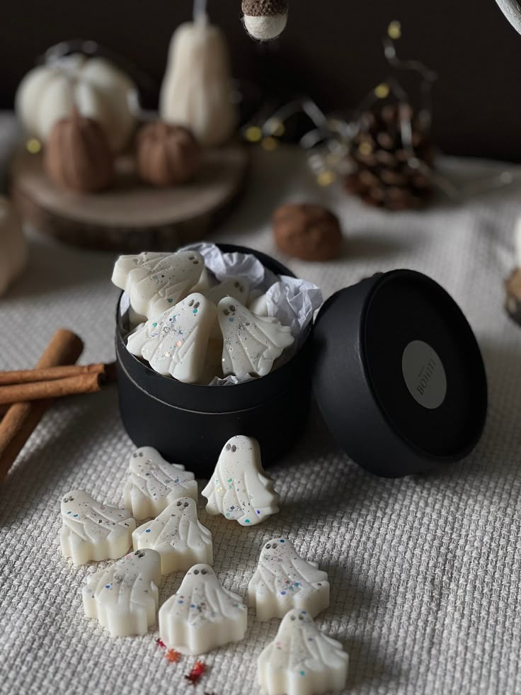 a bowl filled with white frosted cookies on top of a table next to cinnamon sticks