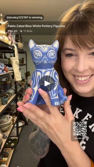 a woman holding up a blue ceramic cat