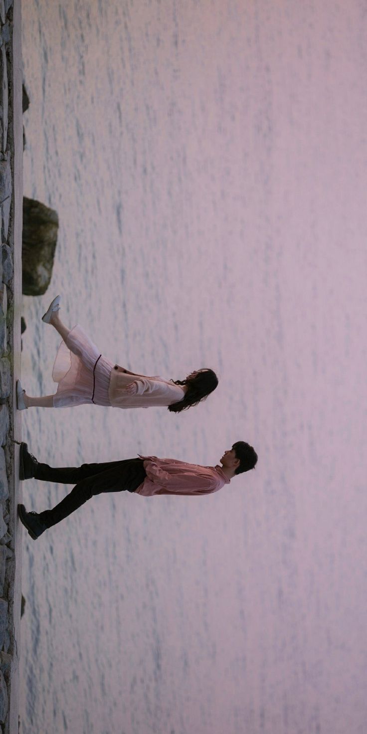 two people standing next to each other on the beach