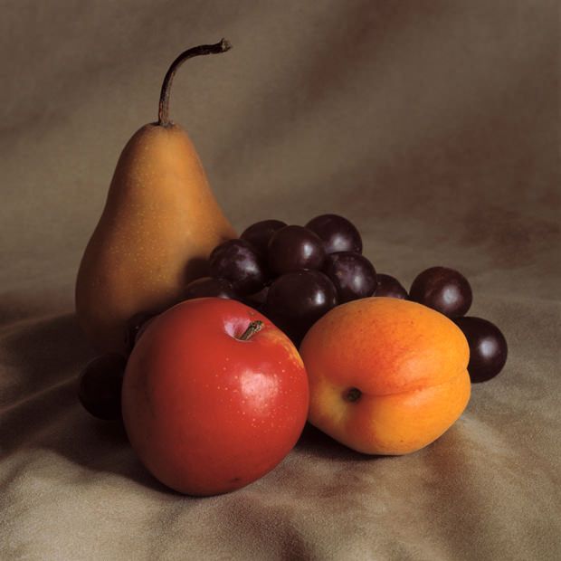 two pears, an orange and some blackberries on a tablecloth with a white background