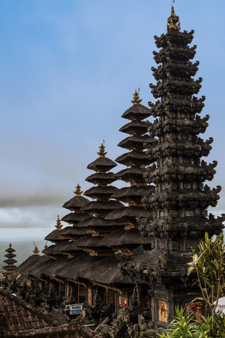 an elaborately designed building stands in front of the ocean and sky, surrounded by tropical vegetation