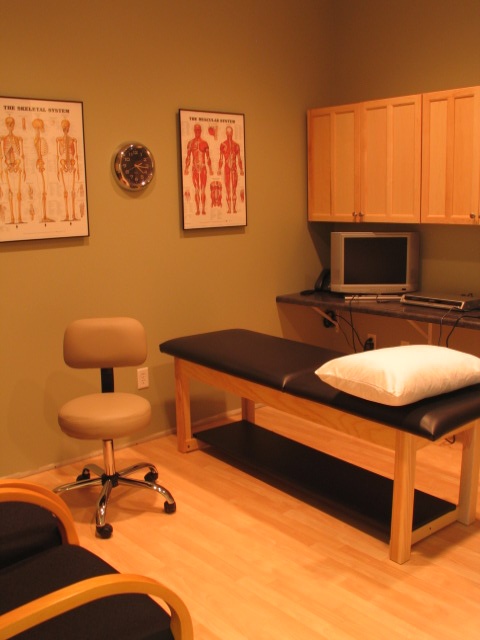 an exam room with chairs, desks and pictures on the wall above it that are also in front of a computer