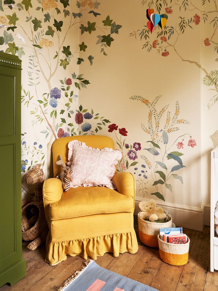 a yellow chair sitting in front of a wall with colorful flowers on it's walls