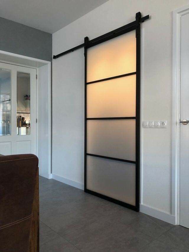 an open sliding door in a room with white walls and brown leather chair next to it