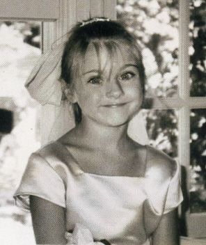 a black and white photo of a woman in a wedding dress sitting at a table