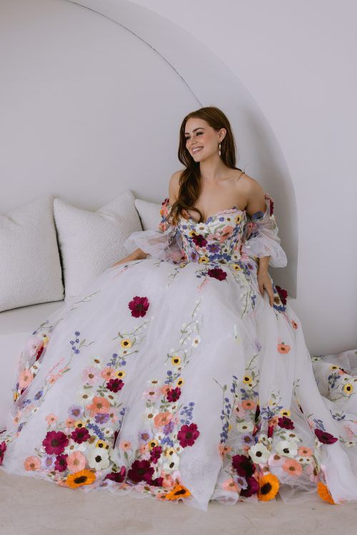 a woman in a white dress sitting on a couch with flowers all over her body