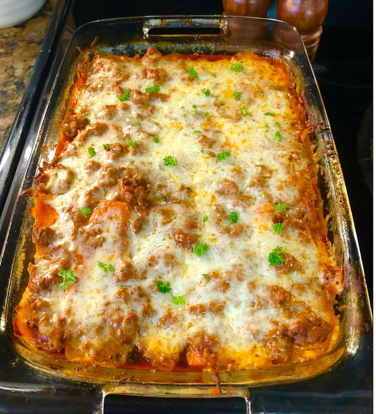 a casserole dish with meat and cheese in it sitting on a stove top