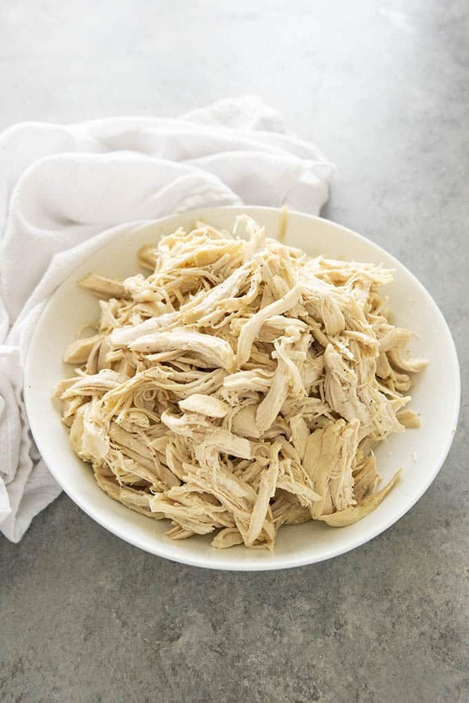 shredded chicken in a white bowl on top of a table with text overlay that reads how to make perfect instant pot shredded chicken