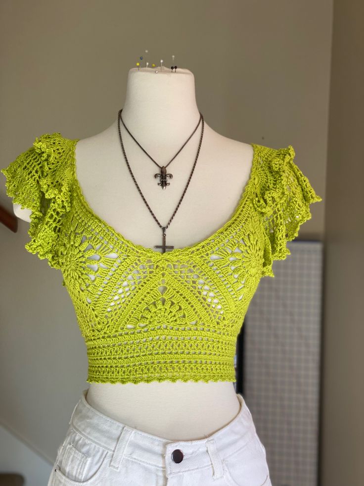 a mannequin wearing a yellow top and white shorts with a necklace on it