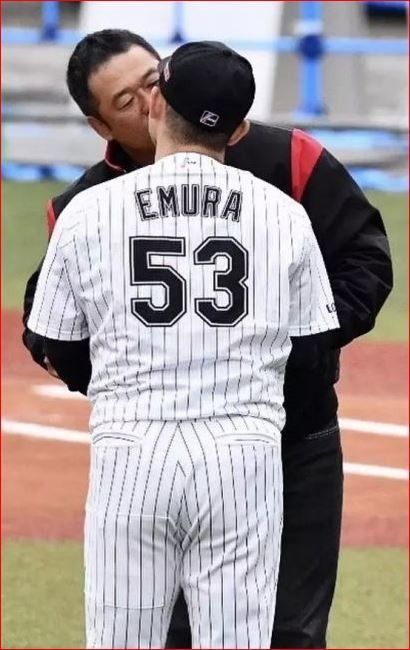 two baseball players standing next to each other on a field with one kissing the other