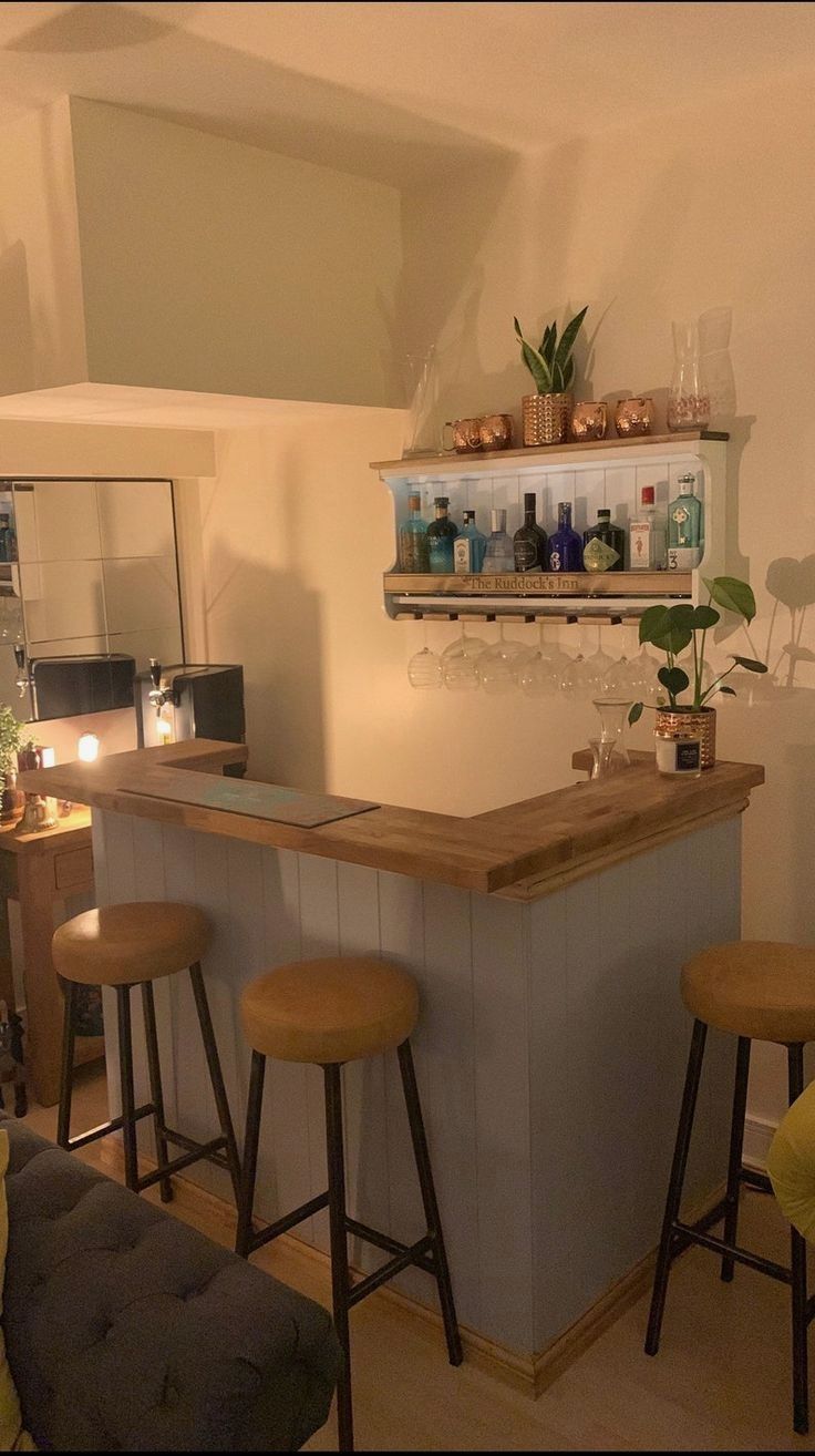 a bar with three stools in front of it and shelves on the wall above