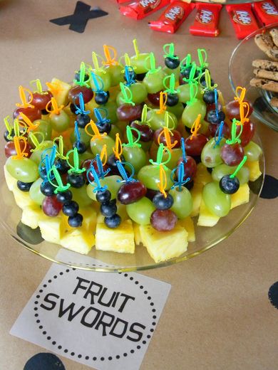 a platter filled with grapes, pineapples and blueberries next to cookies