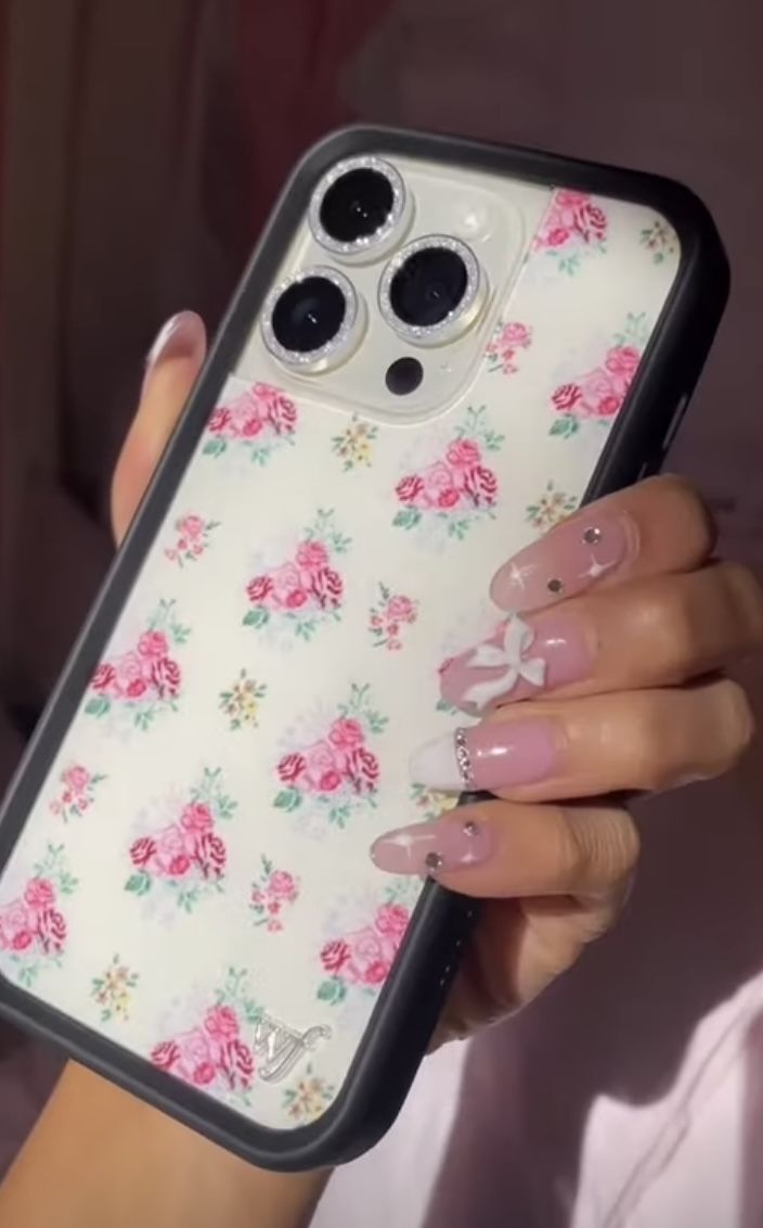 a woman holding up her phone case with pink flowers on the front and bottom cover