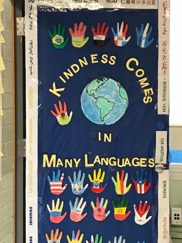 a bulletin board with many hand prints on it that says kindness comes in many languages