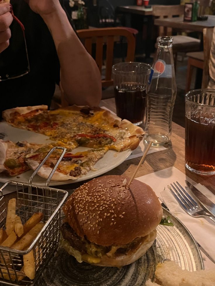 a person sitting at a table with a plate of food and a basket of fries