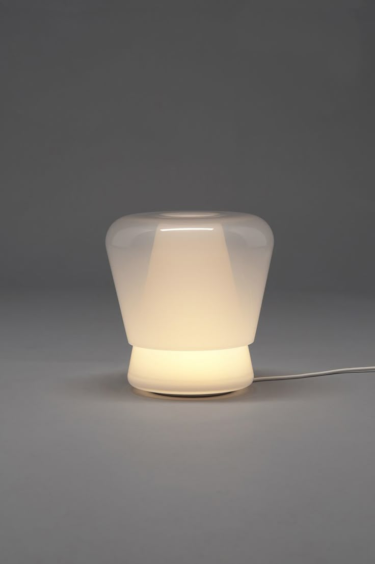 a white light sitting on top of a table next to a gray wall and floor