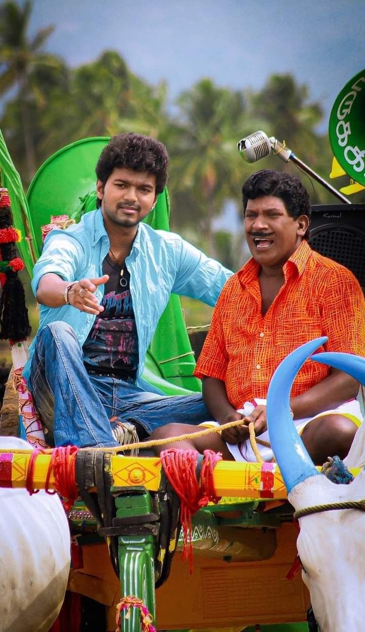 two men are sitting in the back of a horse drawn carriage with colorful decorations on it