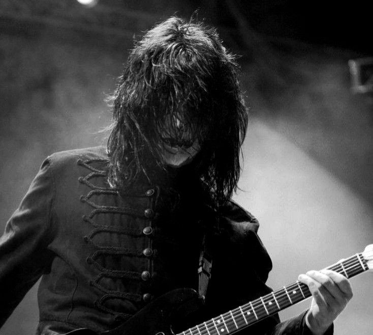 a man with long hair playing an electric guitar