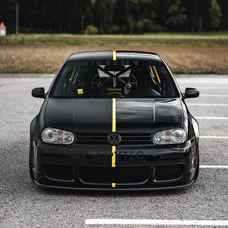 a black car with yellow stripes parked in a parking lot