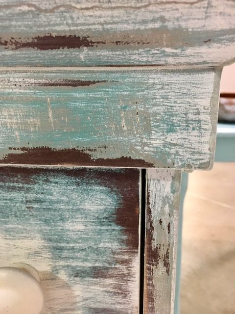 an old blue and white dresser with knobs on the drawer pulls up to show paint chipping off