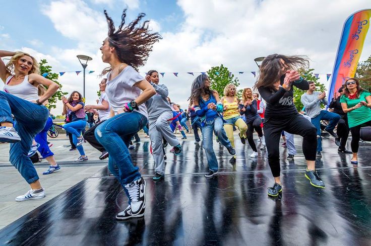 a group of young women dancing on top of a black surface in front of a crowd