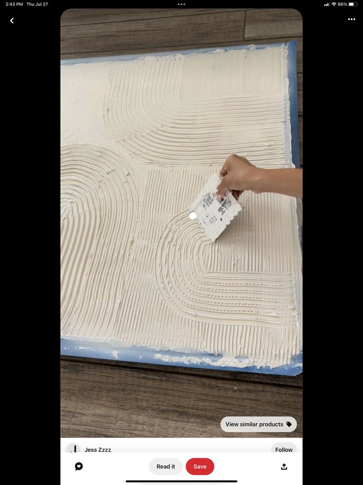 someone is using a brush to paint the floor in front of a large piece of wood