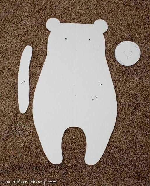 a cutout of a bear and a ball on a brown carpeted floor with the shape of a teddy bear next to it