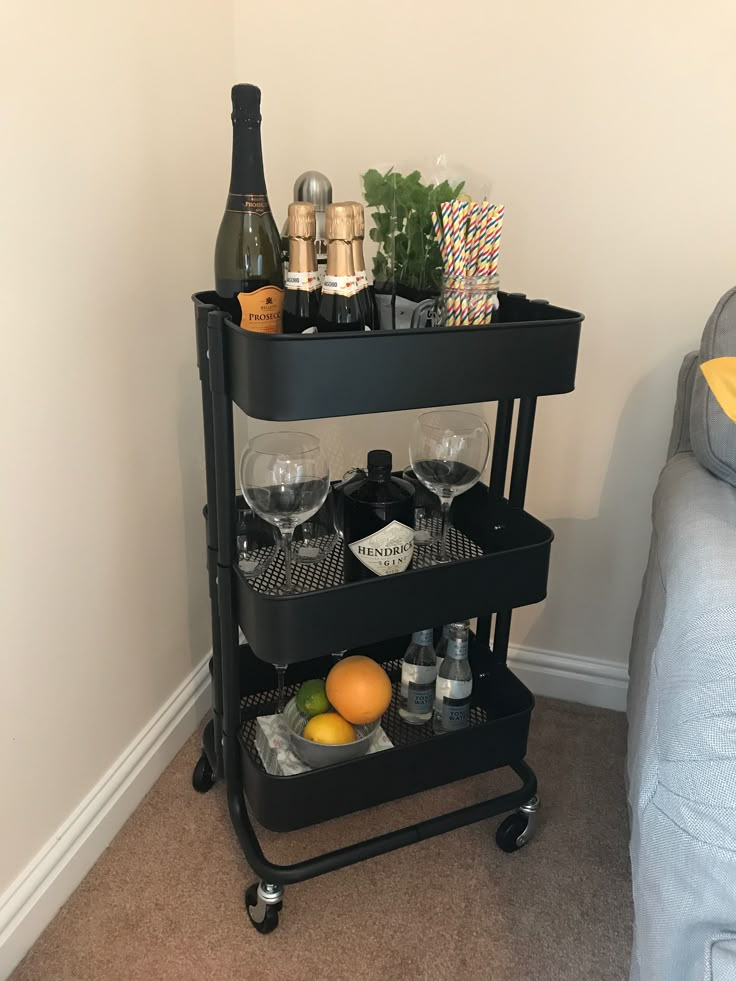 a bar cart with drinks and glasses on it in the corner of a living room