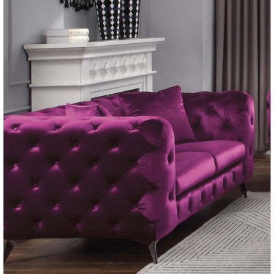 a purple couch sitting in front of a white fireplace