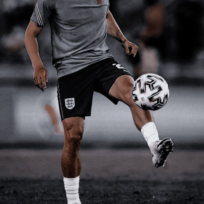 a man kicking a soccer ball on top of a field