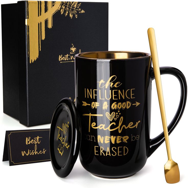 a black coffee mug with gold lettering on it and a matching spoon in front of the box